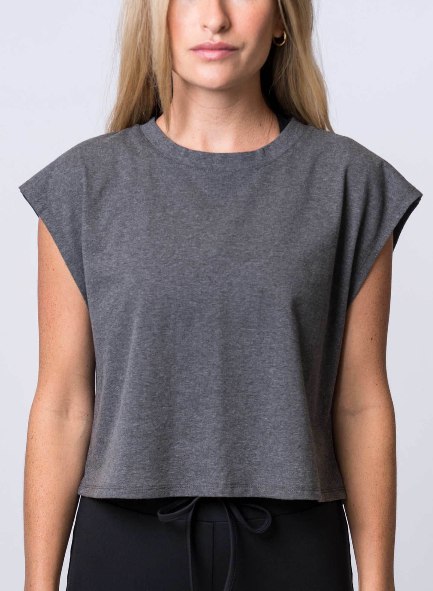 Woman wearing a dark gray, crop top with black drawstring lounge pants. Front of clothing is being shown