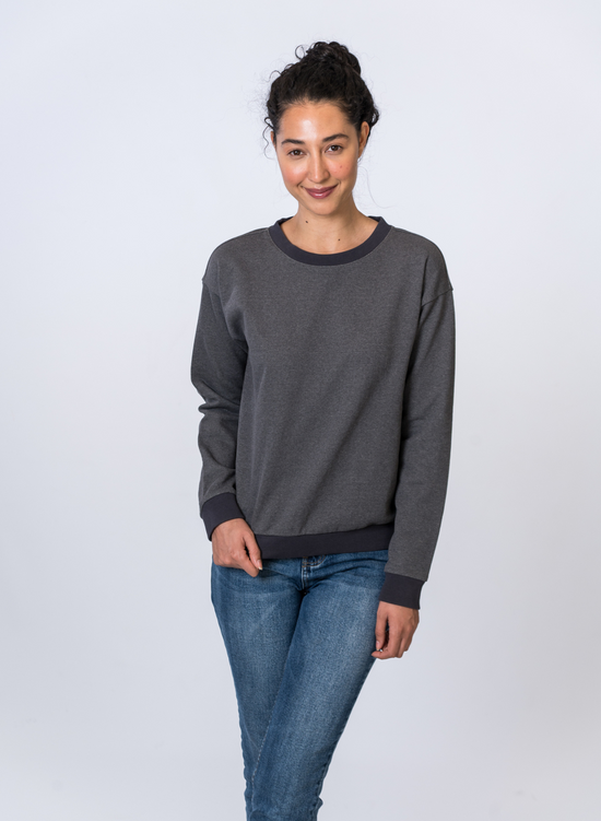Load image into Gallery viewer, Woman smiling, wearing a dark gray crewneck with medium wash jeans. Front of clothing is being shown
