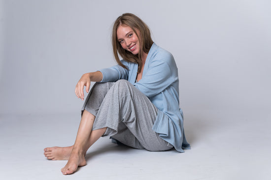 Load image into Gallery viewer, Woman sitting down, wearing a light blue tie robe with gray lounge pants. Front and side of clothing is being shown
