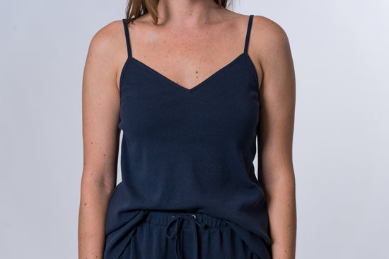 Woman wearing a dark blue tank top and matching drawstring lounge pants. Front of clothing is being shown