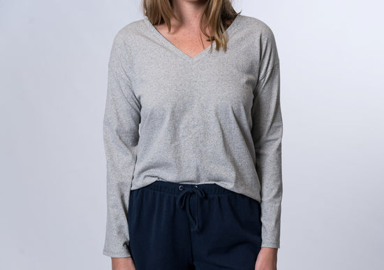 Woman wearing a gray, long sleeve lounge top with navy blue drawstring lounge shorts. Front of clothing is being shown