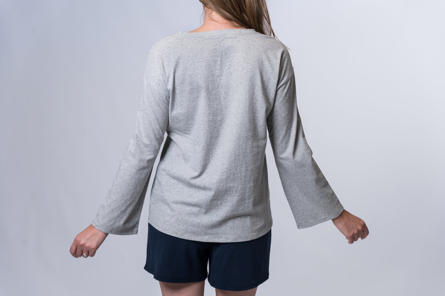 Load image into Gallery viewer, Woman wearing a gray, long sleeve lounge top with navy blue drawstring lounge shorts. Back of clothing is being shown
