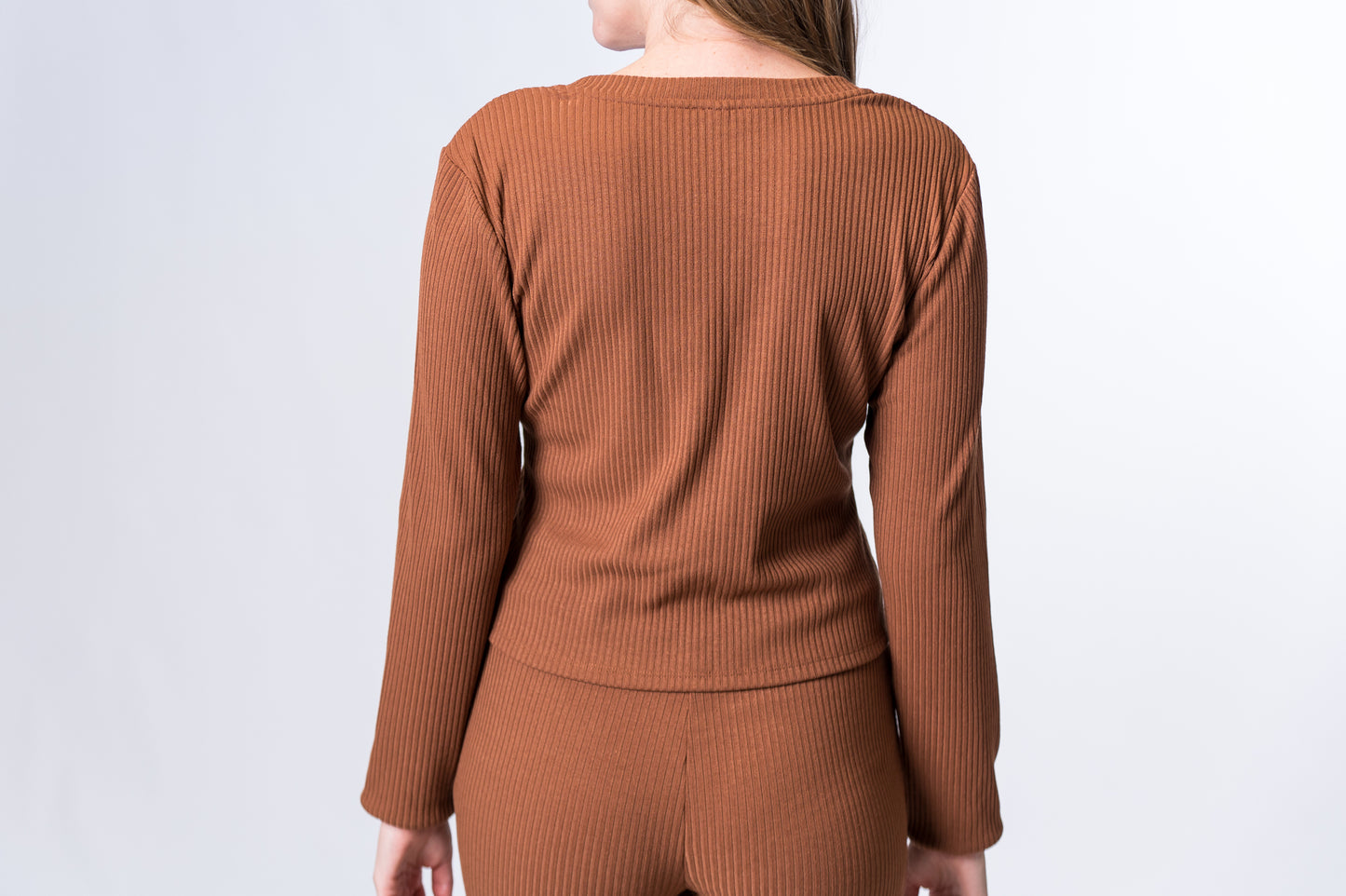 Woman wearing a brown, ribbed long sleeve lounge top with matching pants. Back of clothing is being shown