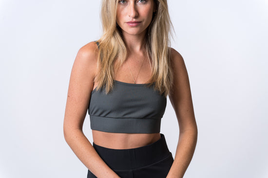 Woman wearing a gray, ribbed bra and black lounge pants. Front of clothing is being shown
