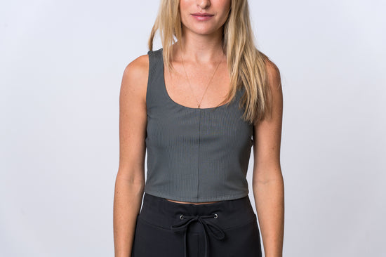 Woman wearing a gray, ribbed bra top with black drawstring lounge pants. Front of clothing is being shown