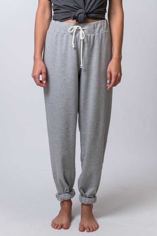 Load image into Gallery viewer, Woman wearing light gray, drawstring sweatpants rolled at the bottom, with a dark gray, tie knot top. Front of clothing is being shown
