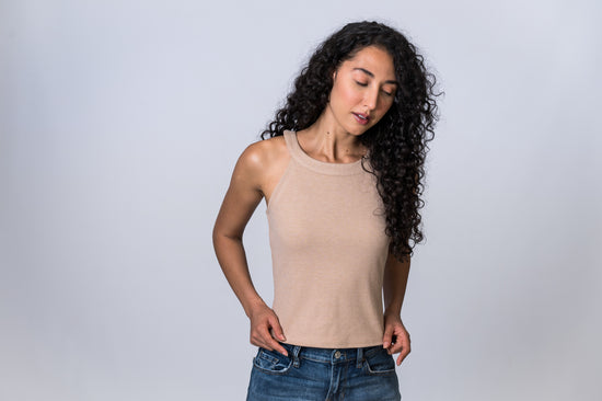 Load image into Gallery viewer, Woman with eyes closed, wearing a tan, round neck tank top with medium wash jeans. Front of clothing is being shown
