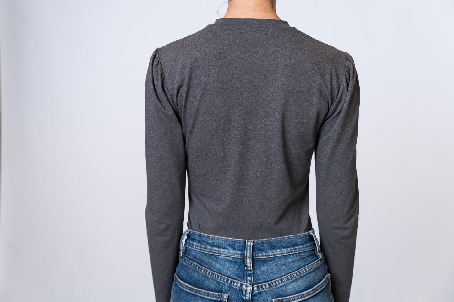 Load image into Gallery viewer, Woman wearing a gray, long sleeve top with puff sleeves and medium wash jeans. Back of clothing is being shown
