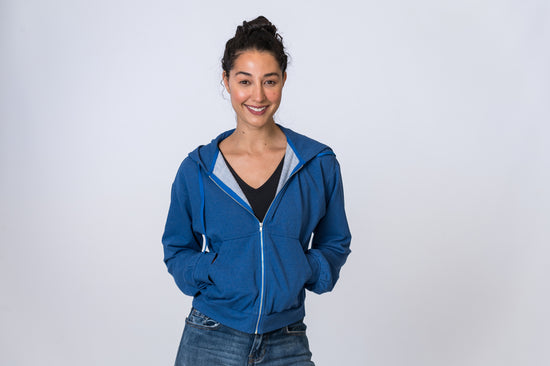Load image into Gallery viewer, Woman wearing a blue zip up hoodie with a black undershirt and jeans. Front of clothing is being shown
