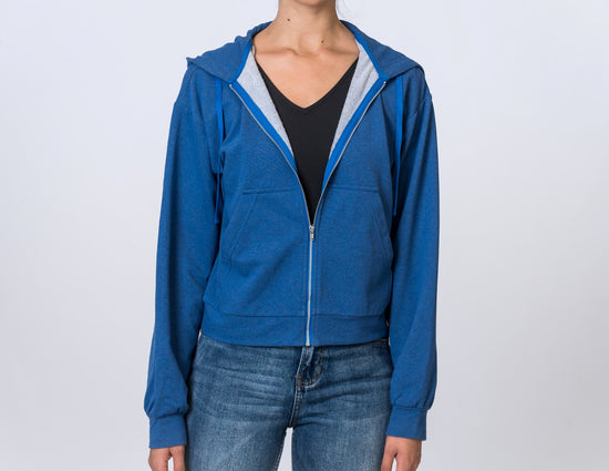 Woman wearing a blue zip up hoodie with a black undershirt and jeans. Front of clothing is being shown