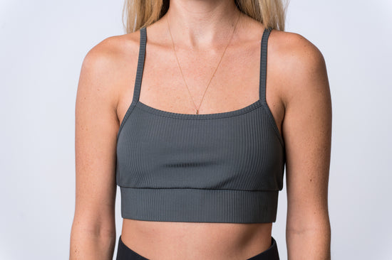 Woman wearing a gray, ribbed bra and black lounge pants. Front of clothing is being shown