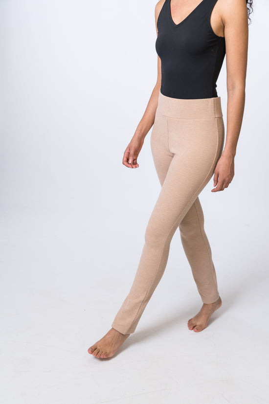 Woman wearing tan, ribbed lounge pants with a black bodysuit. Side and front of clothing is being shown