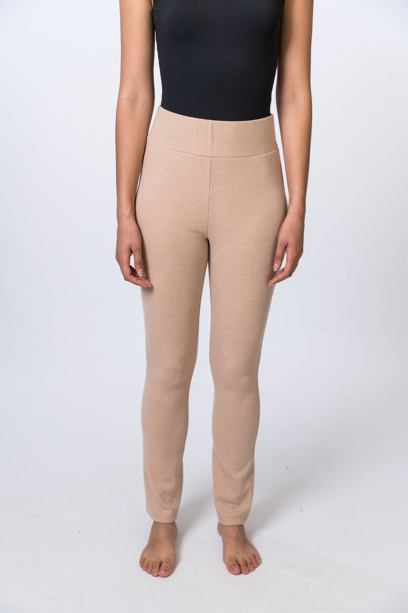 Woman wearing tan, ribbed lounge pants with a black bodysuit. Front of clothing is being shown