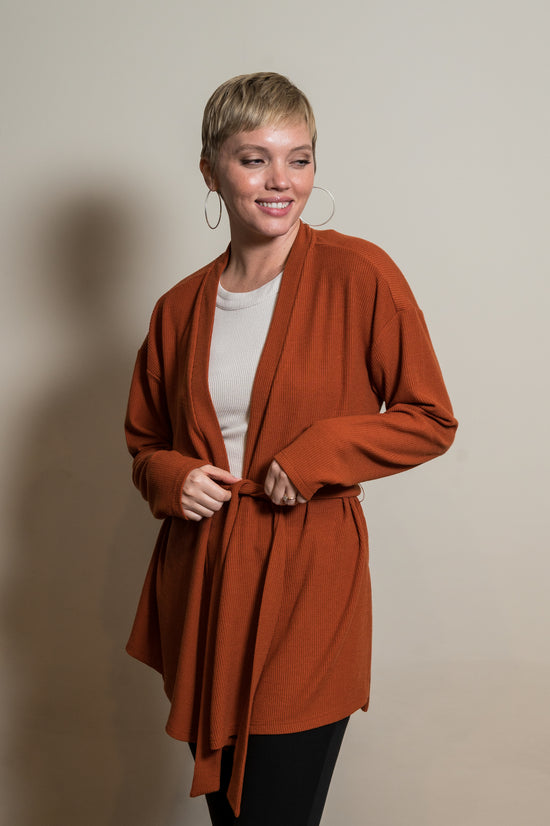 Woman wearing an orange tie robe with white undershirt and black lounge pants. Front of clothing is being shown